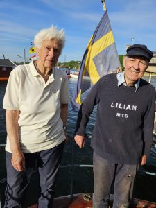 Ett äldre par ombord på en båt. Mannen bär en tröja som det står Lilian på.