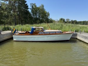 Motorbåt med vitt skrov och träöverbyggnad.