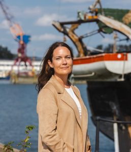 En kvinna fotograferad i framför en båt i docka.
