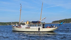 En person på en foilbräda passerar en större lustyacht.