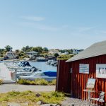 Småbåtshamn på västkusten. Till höger en faluröd sjöbod. På en skylt står det "konst".