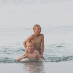 Två unga pojkar som leker i strandbrynet.