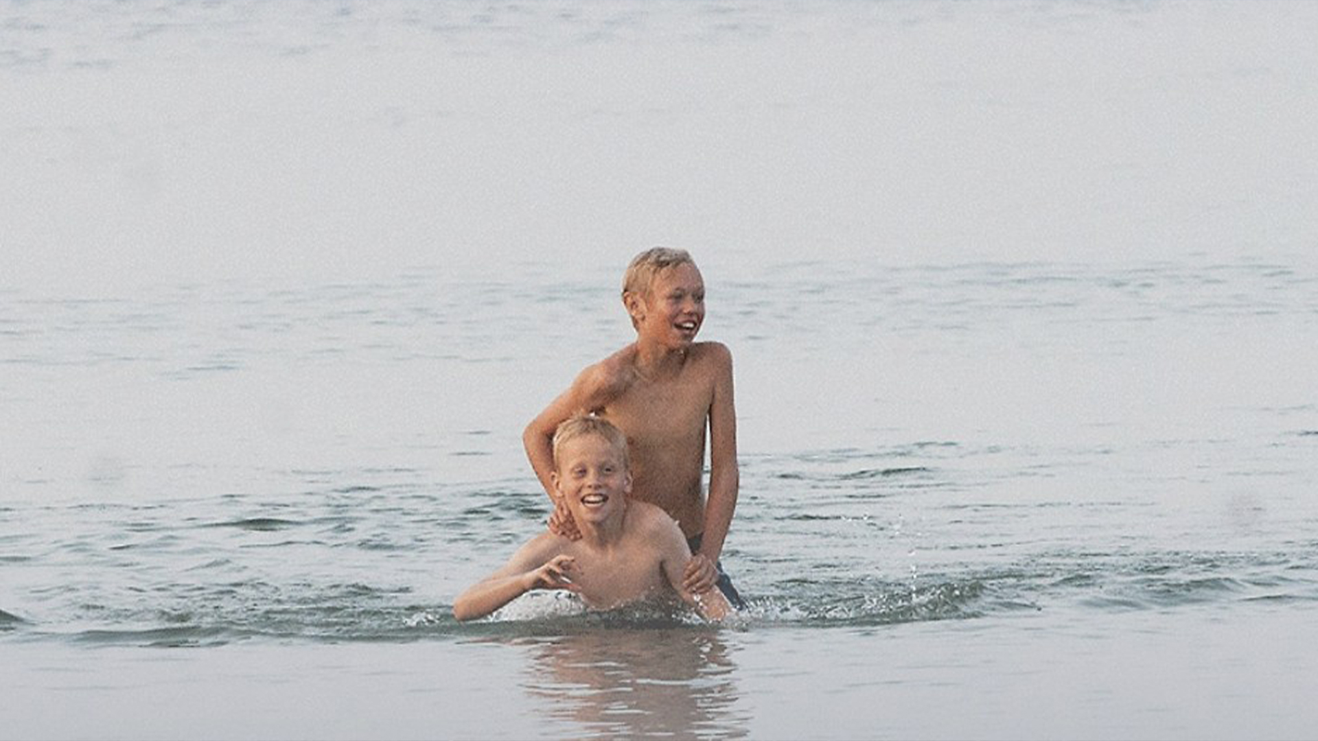 Två unga pojkar som leker i strandbrynet.