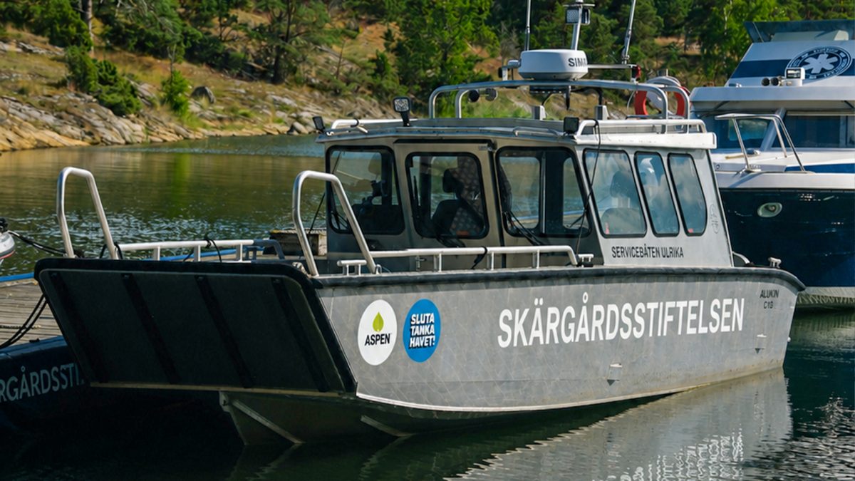 Aluminiumbåt vid brygga. Det står Skärgårdsstiftelsen på båten.