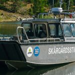 Aluminiumbåt vid brygga. Det står Skärgårdsstiftelsen på båten.