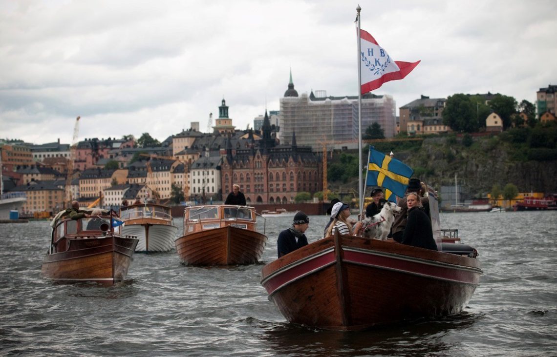 Fyra träbåtar i procession på vattnet i Stockholm.