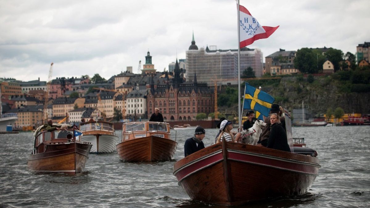 Fyra träbåtar i procession på vattnet i Stockholm.