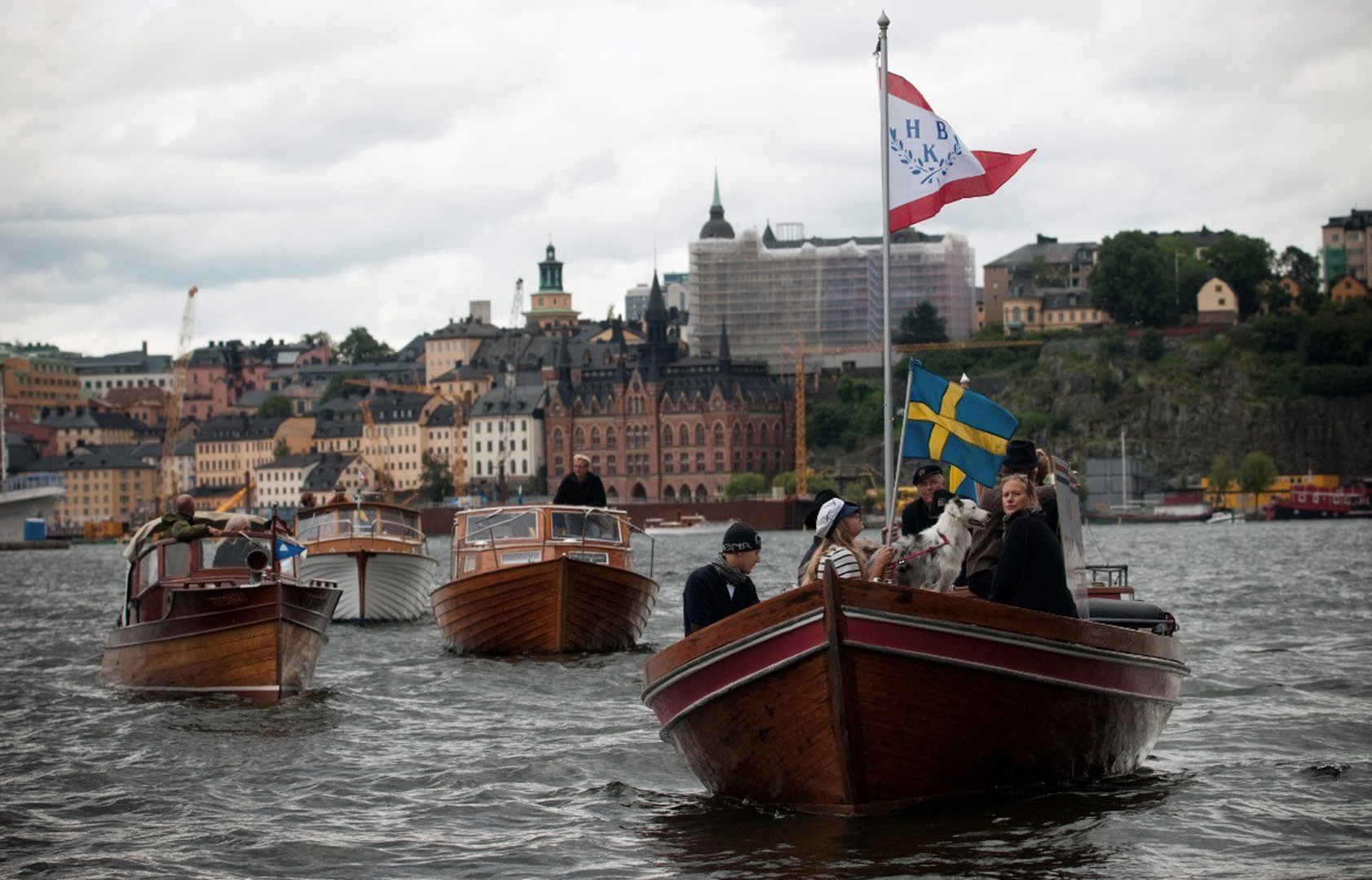 Fyra träbåtar i procession på vattnet i Stockholm.