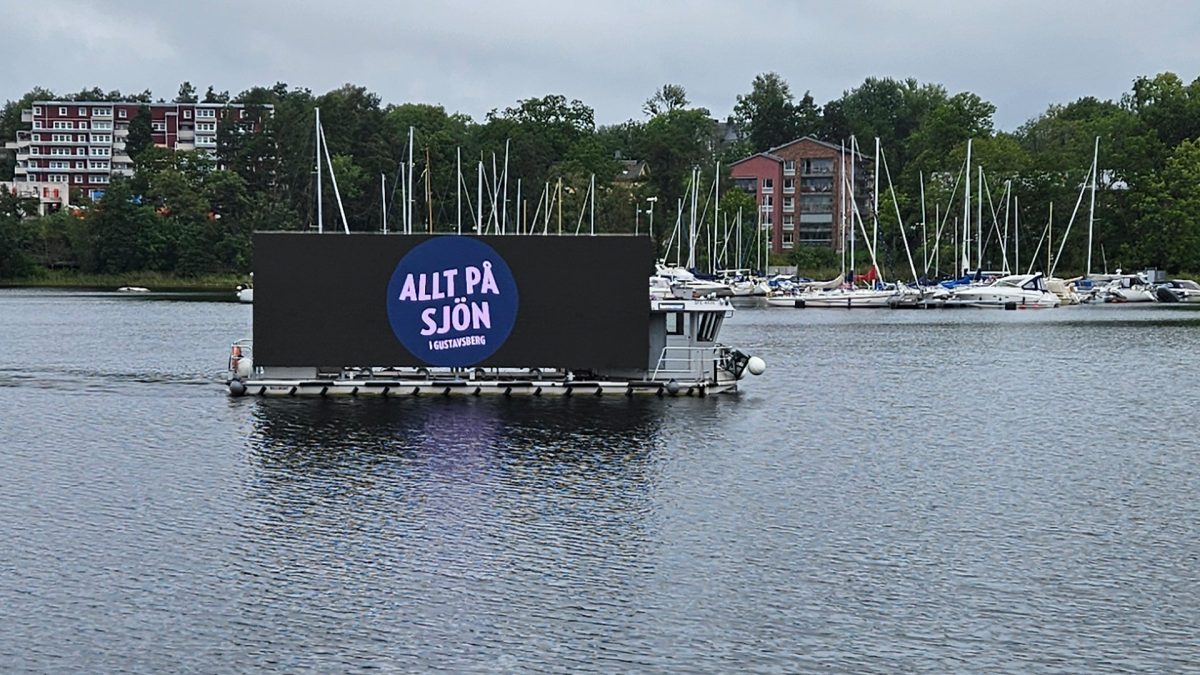 En pråm med en stor bildskärm som det står Allt på sjön på.