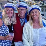 Tre personer, två kvinnor en man, med matrosmössor på sig.